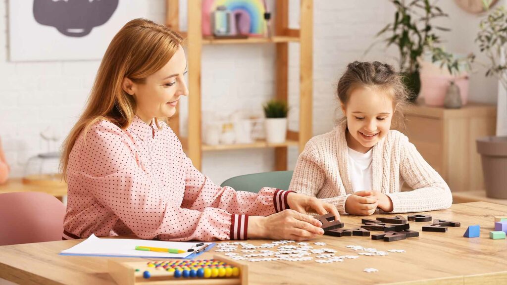 Behavioral therapist working a puzzle with a smiling child