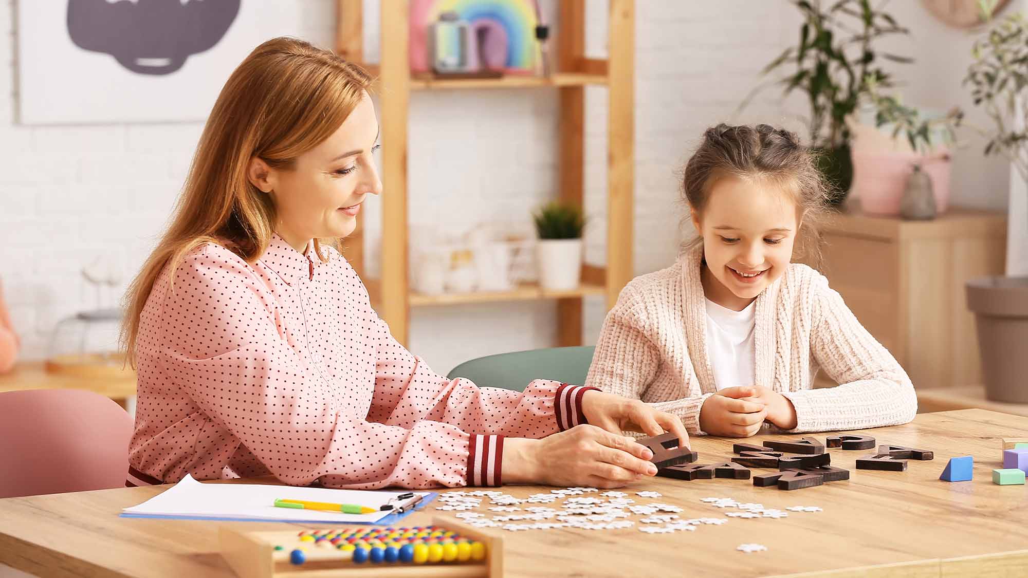 Behavioral therapist working a puzzle with a smiling child