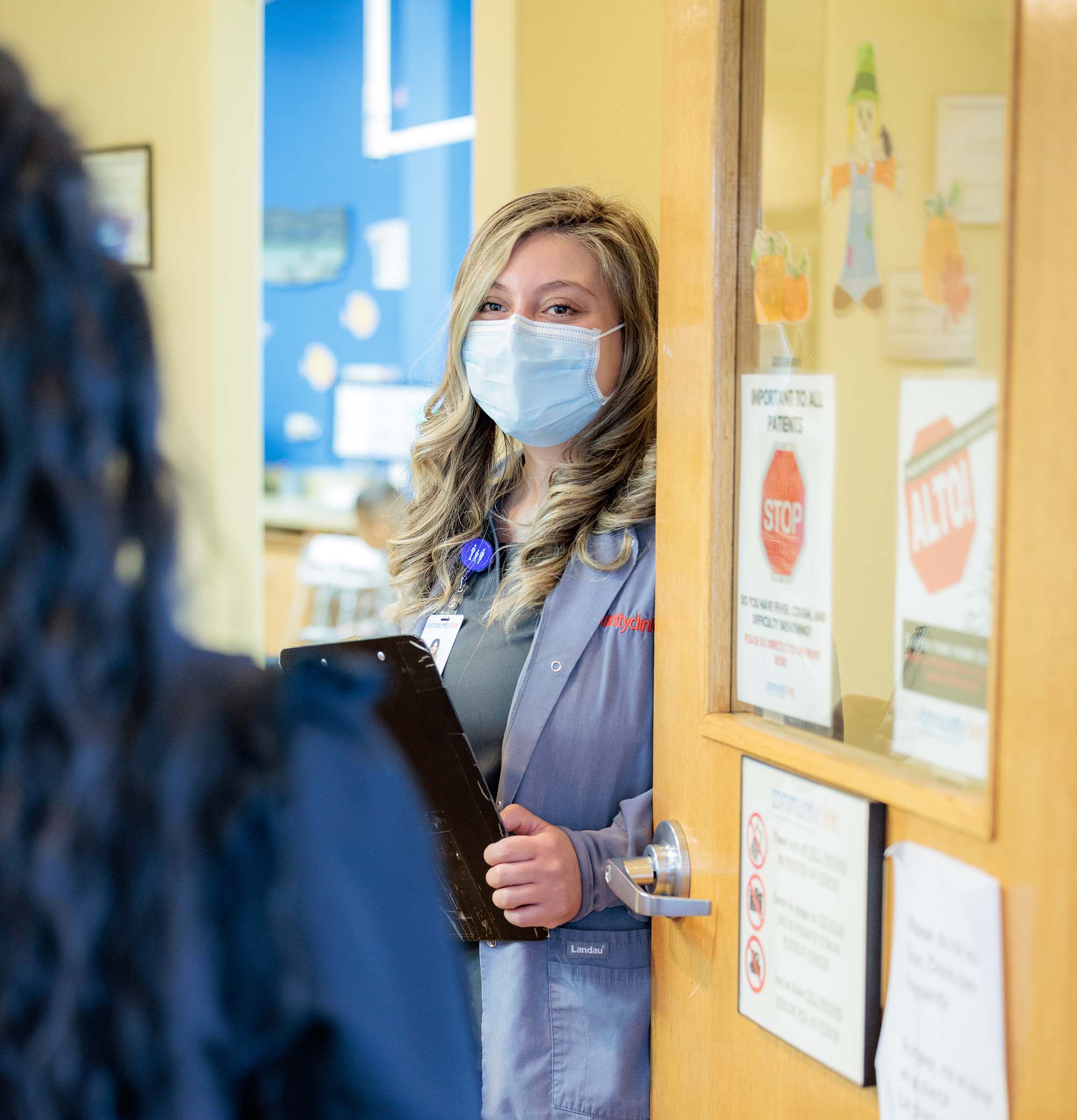 Healthcare provider wearing mask greeting patient at the door