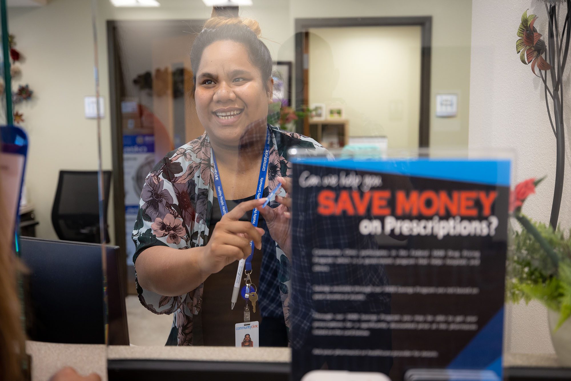 Woman pointing to sign that says, Can we help you save money on prescriptions?